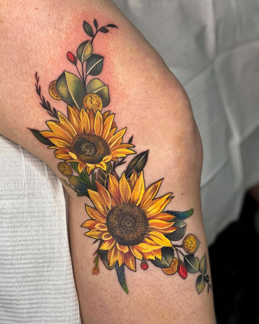 Beautiful sunflower tattoo with floral accents.
