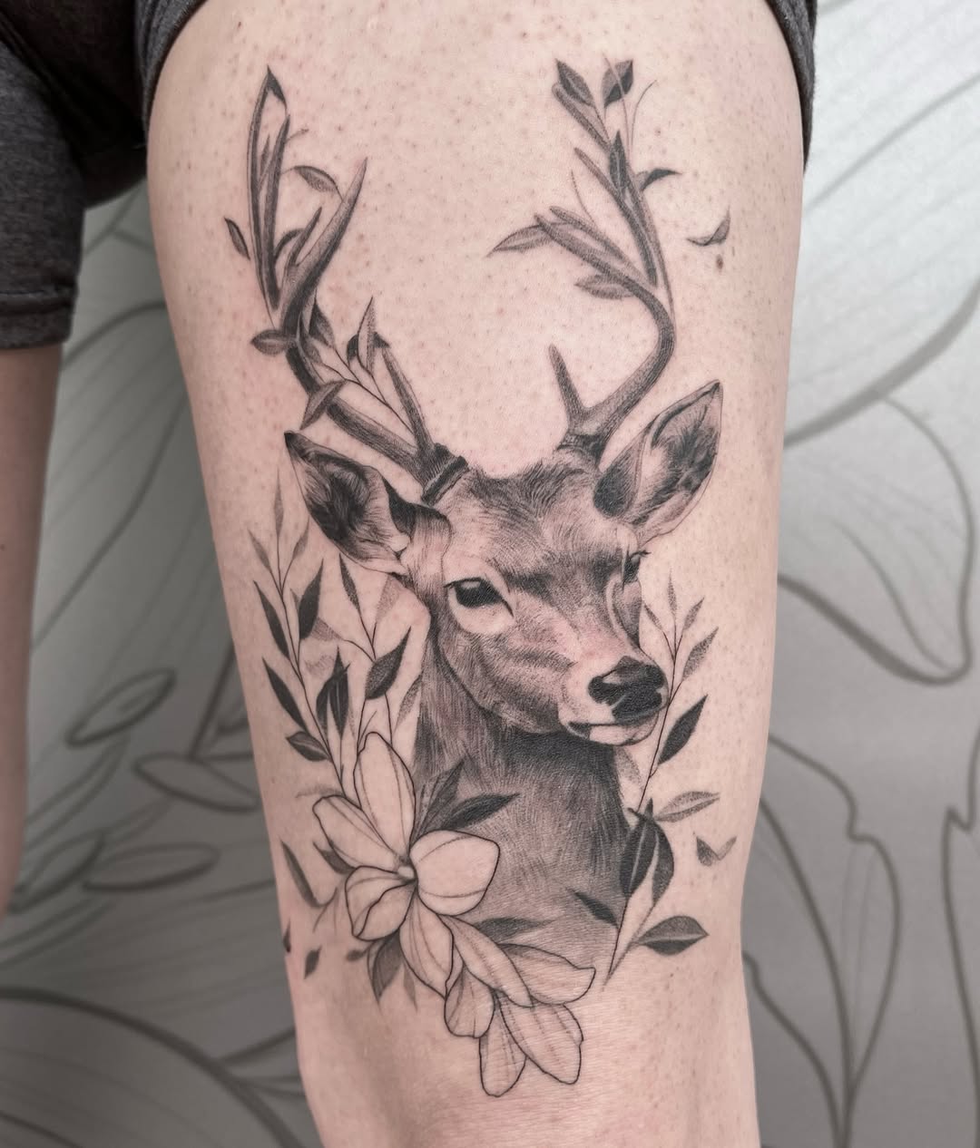 Elegant deer tattoo framed by beautiful flowers