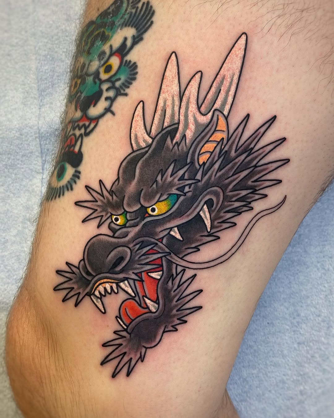 Vibrant dragon tattoo with fierce expression.